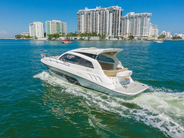 Slide: The Image of Luxury Hanover 375 yacht cruising near modern waterfront buildings, 2025 model. - 4