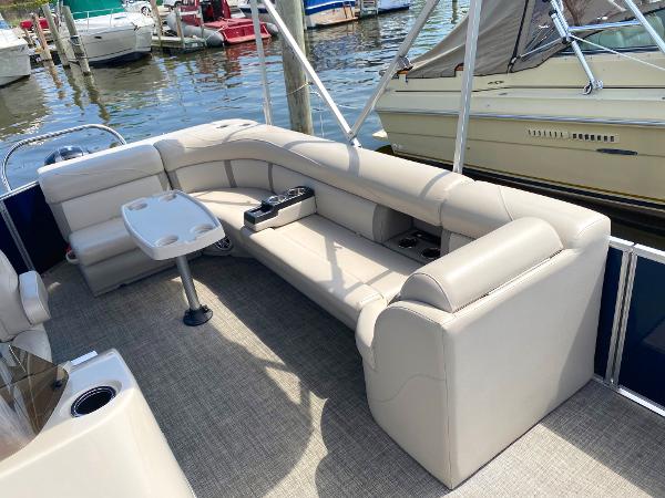 Slide: The Image of 2017 Harris 240 Cruiser pontoon boat with beige seating and table at a marina. - 2