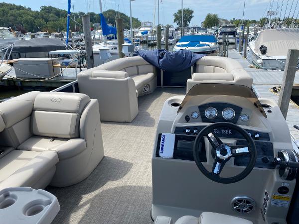 Slide: The Image of 2017 Harris 240 Cruiser pontoon boat at a marina, featuring beige seating and a modern dashboard. - 6