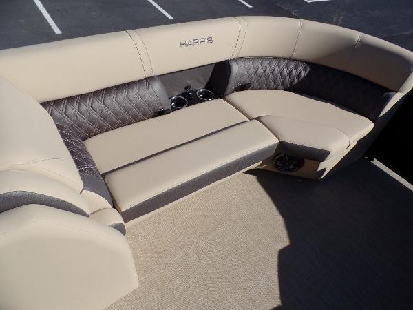 Slide: The Image of 2024 Harris Sunliner 230 boat interior with beige and black cushioned seating. - 2