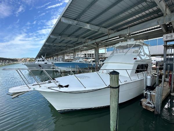 Slide: The Image of 1986 Hatteras 52 Convertible yacht docked under a covered marina. - 0