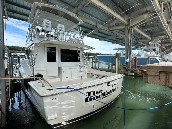 Slide: The Image of 1986 Hatteras 52 Convertible yacht docked in a marina under a covered structure. - 1