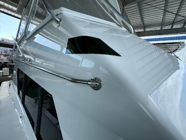 Slide: The Image of 1986 Hatteras 52 Convertible yacht, sleek white exterior, docked under a metal roof. - 12