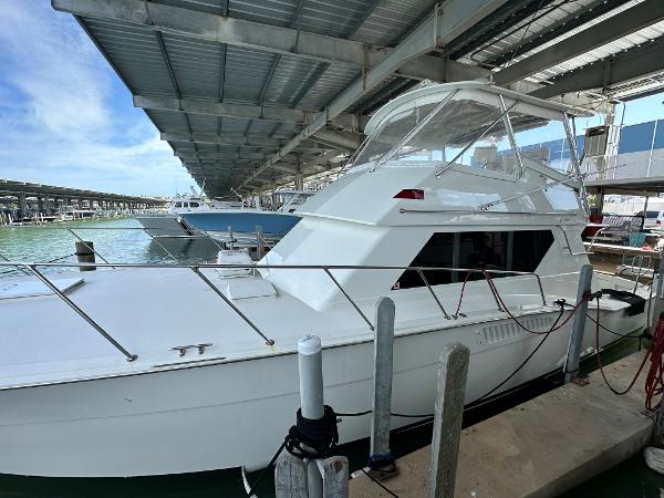 Slide: The Image of 1986 Hatteras 52 Convertible yacht docked under a covered marina. - 2
