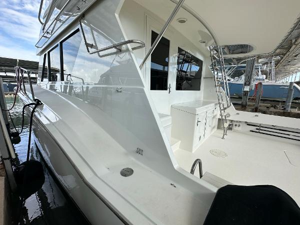 Slide: The Image of 1986 Hatteras 52 Convertible yacht docked, showcasing sleek white exterior and spacious deck. - 6