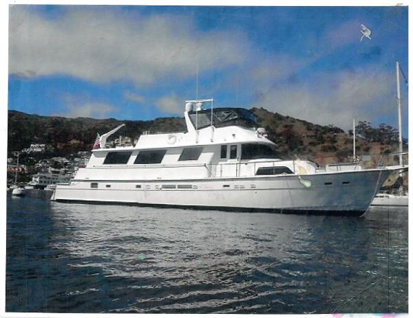 Slide: The Image of 1986 Hatteras 70' Cockpit Motor Yacht anchored in a scenic bay. - 0