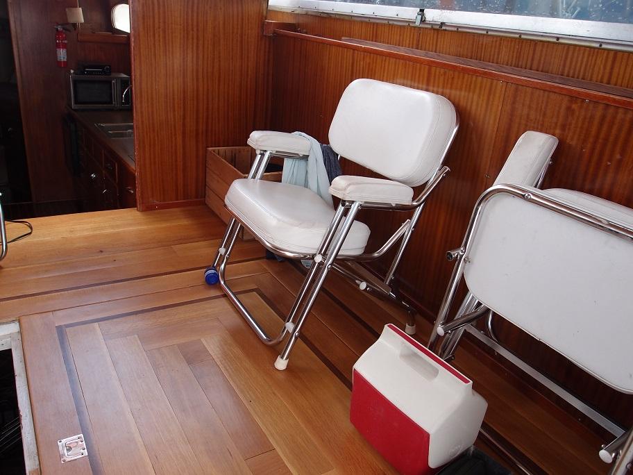 Slide: The Image of Interior of 1961 Hatteras Convertible boat with white chairs and wooden flooring. - 13