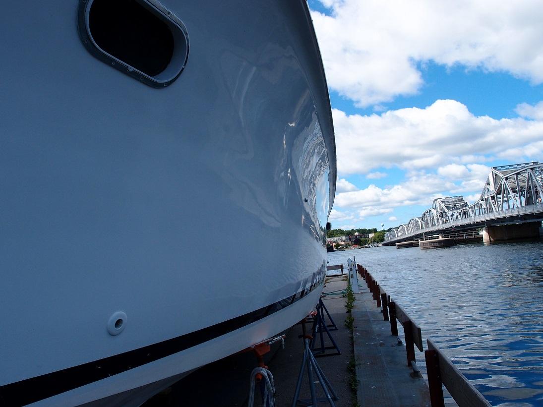 Slide: The Image of 1961 Hatteras Convertible yacht docked near a bridge on a sunny day. - 4