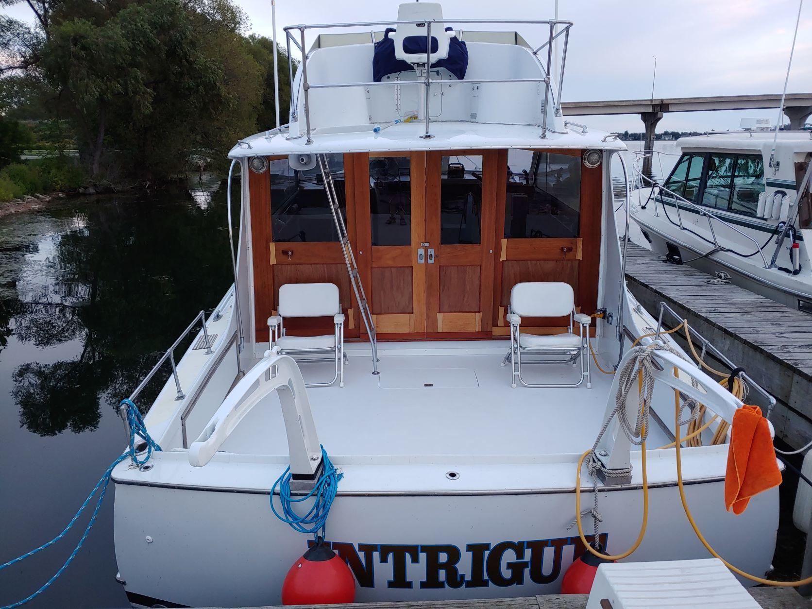 Slide: The Image of 1961 Hatteras Convertible boat docked, featuring wooden doors and deck chairs. - 7