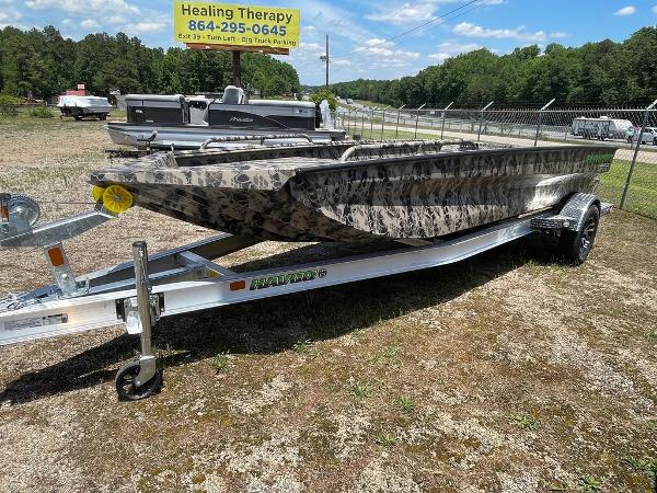 Slide: The Image of 2022 Havoc 1860 Dbst boat on trailer, camo design, parked outdoors. - 0