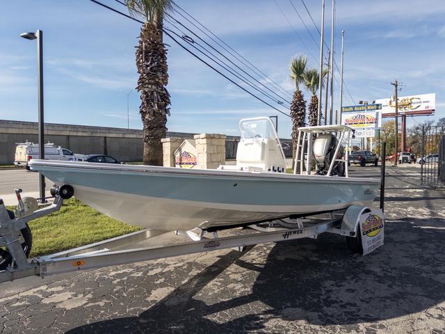 Slide: The Image of 2024 Hewes Redfisher 18 boat on trailer, parked near palm trees and road. - 2
