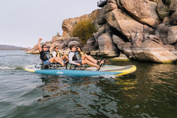 Slide: The Image of Group enjoying a ride on a 2023 Hobie iTrek Fiesta inflatable kayak near rocky cliffs. - 2