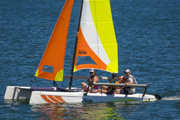 Slide: The Image of 2023 Hobie Cat Getaway sailboat with colorful sails on the water. - 0