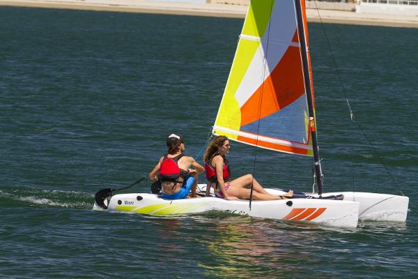 Slide: The Image of 2023 Hobie Cat Wave sailboat with two people sailing on a sunny day. - 0