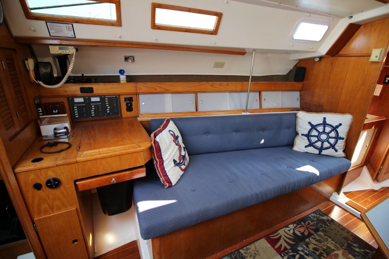 Slide: The Image of Interior of 1987 Hunter 34 sailboat with blue cushioned seating and nautical-themed pillows. - 15