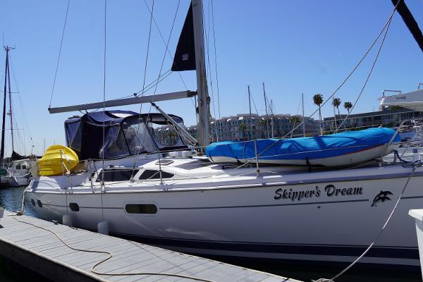 Slide: The Image of Hunter Passage 420 sailboat docked, named "Skipper's Dream," with blue and yellow covers. - 2