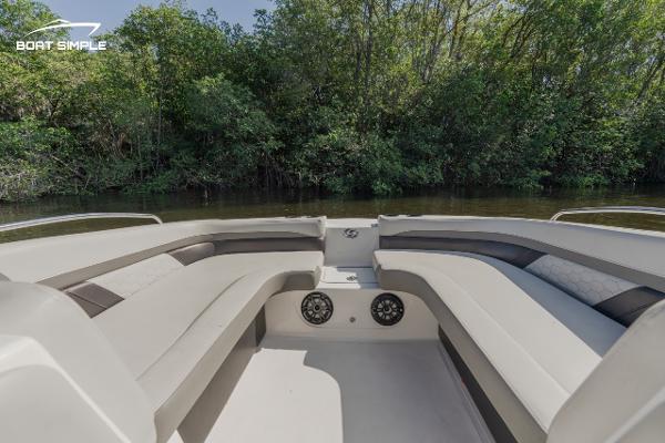 Slide: The Image of 2022 Hurricane 217 SD boat interior with seating and speakers, near lush greenery. - 5