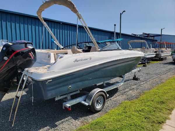Slide: The Image of 2024 Hurricane SunDeck 217 OB boat on trailer, parked outdoors near blue building. - 1