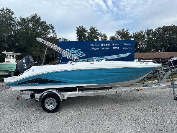 Slide: The Image of 2024 Hurricane SunDeck Sport 185 OB boat on a trailer, displayed outdoors. - 0
