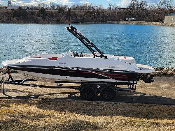 Slide: The Image of 2019 Hurricane SunDeck Sport 202 IO boat on trailer by a lake. - 0