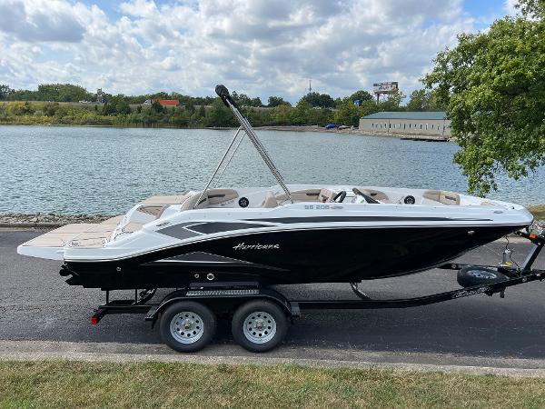 Slide: The Image of 2024 Hurricane SunDeck Sport 205 IO boat on trailer by a lake. - 0
