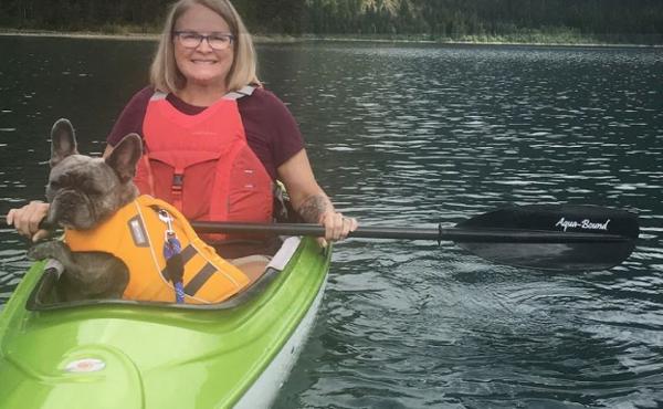 Slide: The Image of Woman kayaking with dog in a 2023 Hurricane Kayaks Santee 116 Sport on a lake. - 2