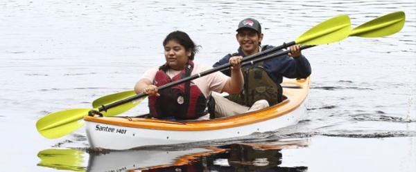 Slide: The Image of Two people kayaking in a 2023 Hurricane Kayaks Santee 140 Tandem. - 2