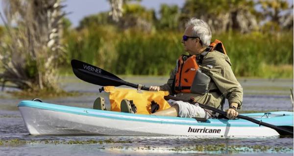 Slide: The Image of Man kayaking in a 2023 Hurricane Kayaks Skimmer 106 on a calm lake. - 8