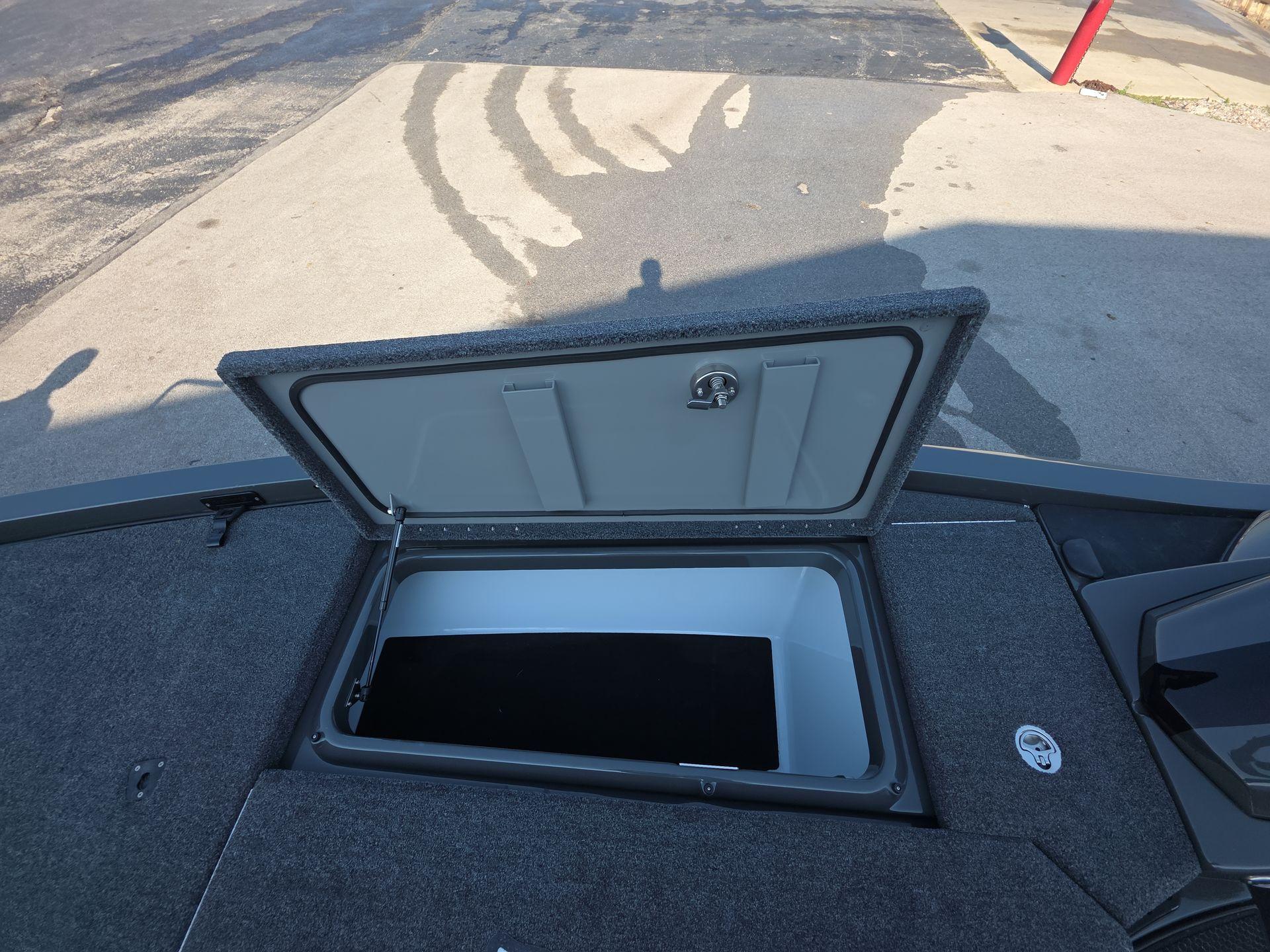 Slide: The Image of Open storage compartment on iKon LX21 boat, 2025 model, with gray carpeted surface. - 10