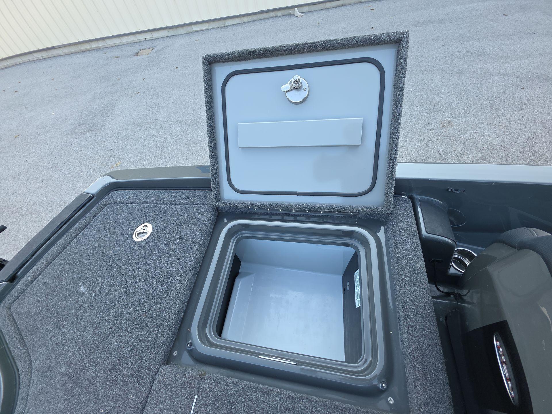 Slide: The Image of Open storage compartment on 2025 iKon LX21 boat, featuring a secure latch and carpeted surface. - 20