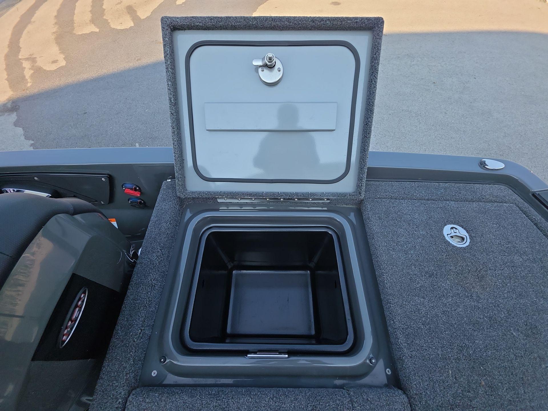 Slide: The Image of Open storage compartment on iKon LX21 boat, 2025 model, with gray carpeted surface. - 21