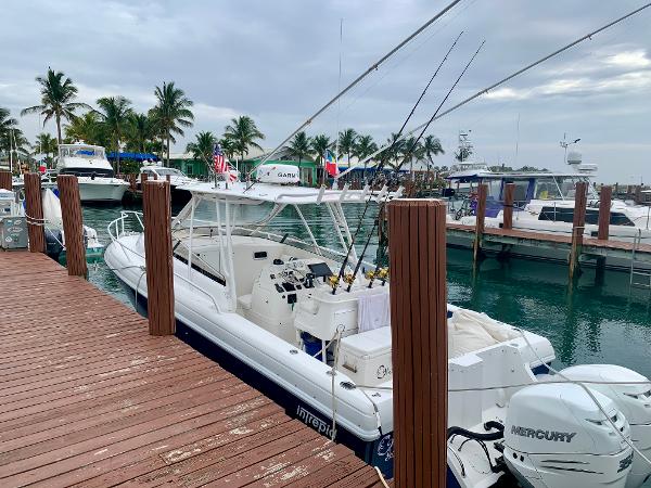 Slide: The Image of 2002 Intrepid 348 Walkaround boat docked at a marina with fishing rods. - 3