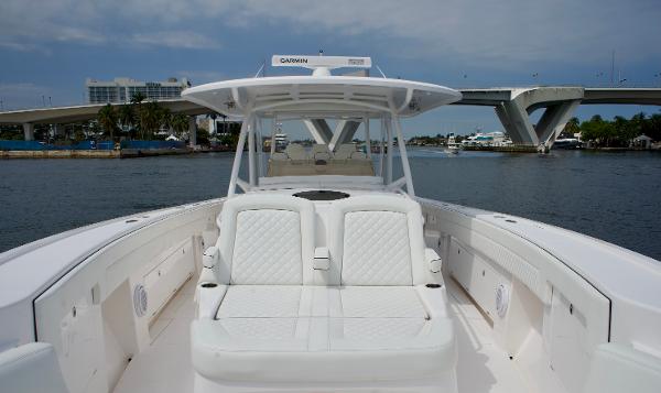 Slide: The Image of 2023 Intrepid 475 Panacea luxury boat with white seating, docked near a bridge. - 10