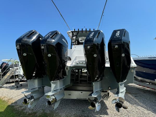 Slide: The Image of 2024 Invincible 40 Catamaran with four powerful outboard engines, docked on gravel. - 7