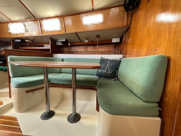 Slide: The Image of Interior of 1983 Irwin Citation 34 sailboat with green cushioned seating and wooden table. - 6
