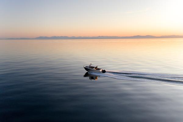 Slide: The Image of 2025 Jasper Marine Defender 22 boat cruising on calm water at sunset. - 10
