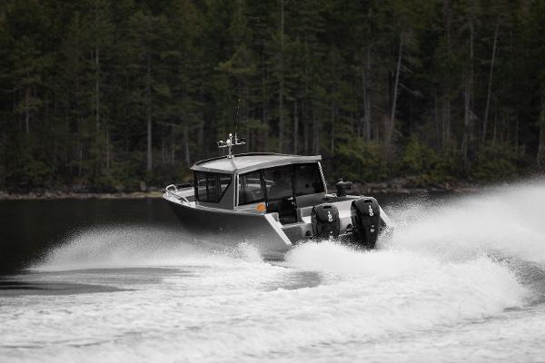 Slide: The Image of 2025 Jasper Marine Defender 22 boat speeding on a lake with forest background. - 18