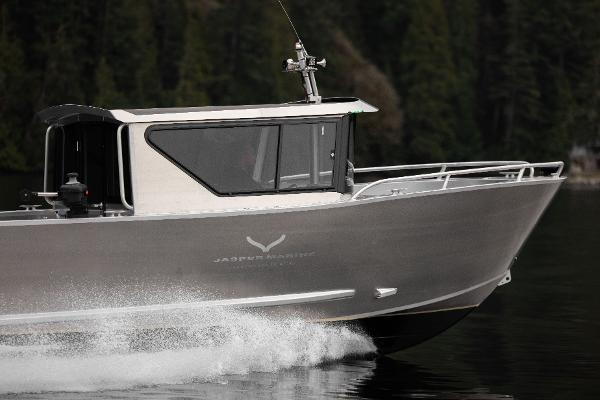 Slide: The Image of 2025 Jasper Marine Defender 22 boat cruising on a lake with forest background. - 20