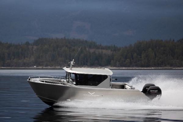 Slide: The Image of 2025 Jasper Marine Defender 22 boat cruising on a lake with forested hills in the background. - 22