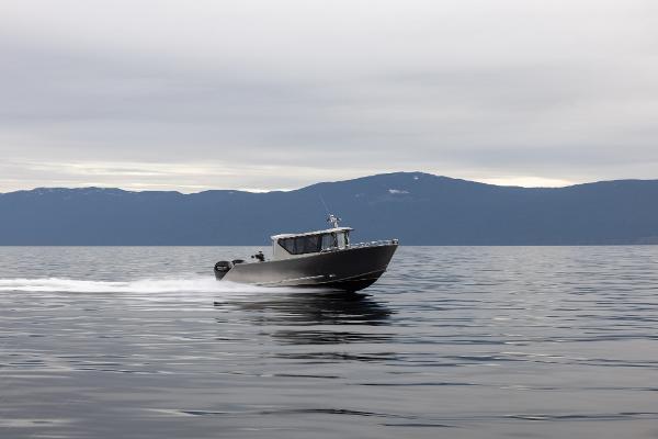 Slide: The Image of 2025 Jasper Marine Defender 22 boat cruising on a calm lake with mountains in the background. - 23