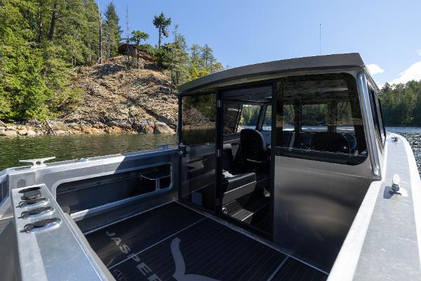 Slide: The Image of 2025 Jasper Marine Defender 22 boat on a scenic lake near rocky shoreline. - 28