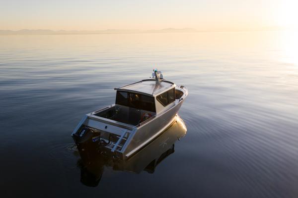 Slide: The Image of 2025 Jasper Marine Defender 22 boat on calm water at sunset. - 5