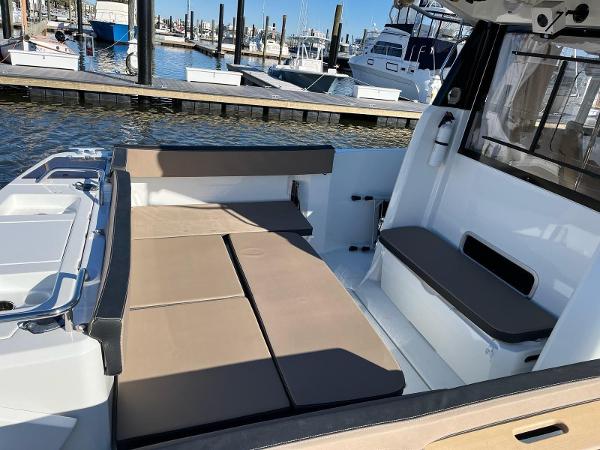 Slide: The Image of 2016 Jeanneau Merry Fisher 855 boat interior with seating and docked boats in the background. - 18