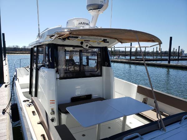Slide: The Image of 2016 Jeanneau Merry Fisher 855 boat docked, featuring outdoor seating and table. - 6