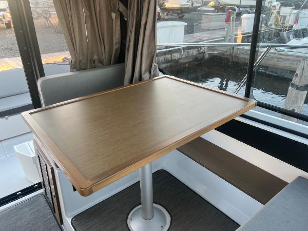 Slide: The Image of Interior of 2020 Jeanneau NC 895 boat with wooden table and seating area. - 10