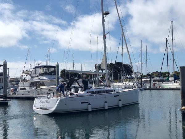 Slide: The Image of 2020 Jeanneau Sun Odyssey 389 sailboat docked in a marina under a partly cloudy sky. - 0