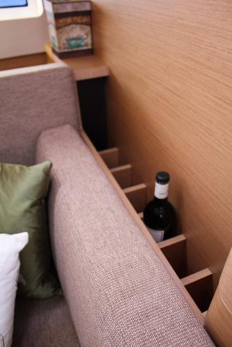 Slide: The Image of 2024 Jeanneau Sun Odyssey 440 interior with wine storage behind sofa. - 21
