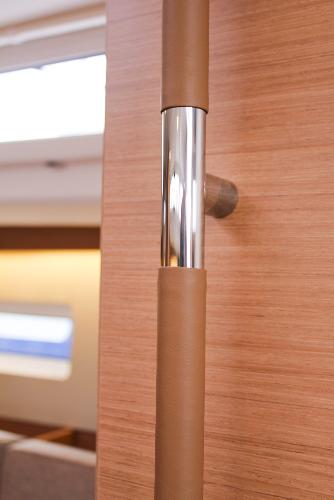 Slide: The Image of 2024 Jeanneau Sun Odyssey 440 interior detail with wooden panel and metal handrail. - 30