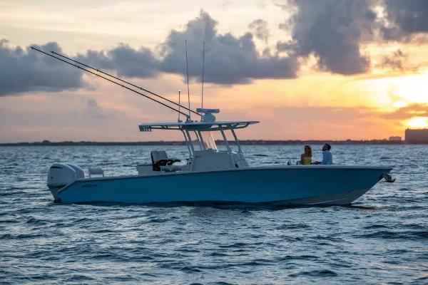 Slide: The Image of 2026 Jupiter 32 boat on water at sunset, featuring fishing rods and two people onboard. - 13