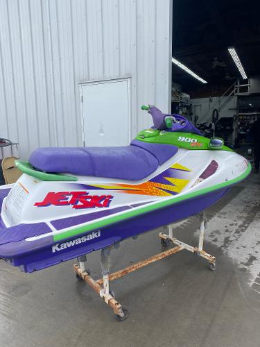 Slide: The Image of 1996 Kawasaki ZXI 900 jet ski with vibrant purple and green design in a garage. - 1